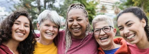 five smiling women stand together arm in arm