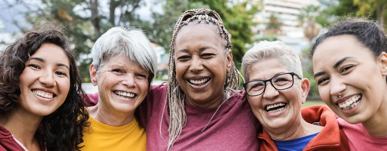 five smiling women stand together arm in arm