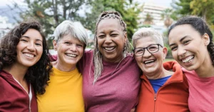 five smiling women stand together arm in arm