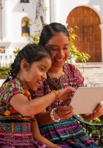 indigenous mother and daughter reading together in a courtyard