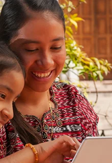 indigenous mother and daughter reading together in a courtyard