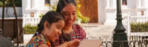 indigenous mother and daughter reading together in a courtyard