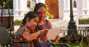 indigenous mother and daughter reading together in a courtyard