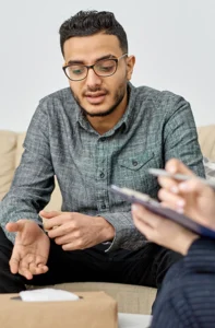 young man sitting on a couch talking to a counselor