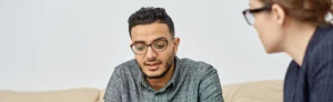 young man sitting on a couch talking to a counselor