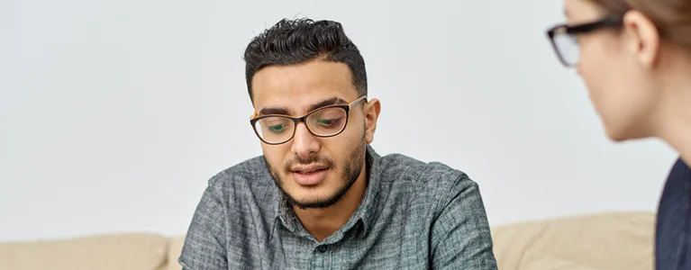 young man sitting on a couch talking to a counselor