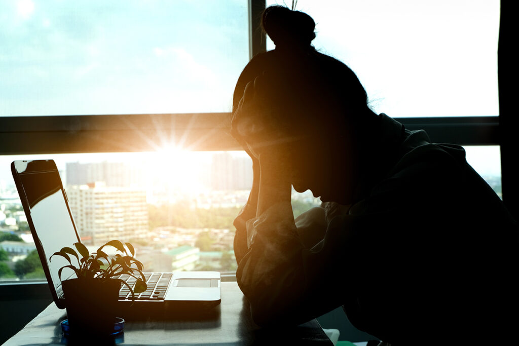 Stressed woman with sun shining in the background.