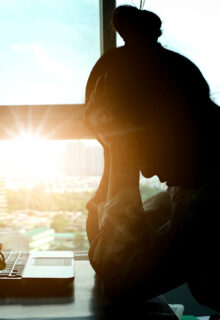 Stressed woman with sun shining in the background.