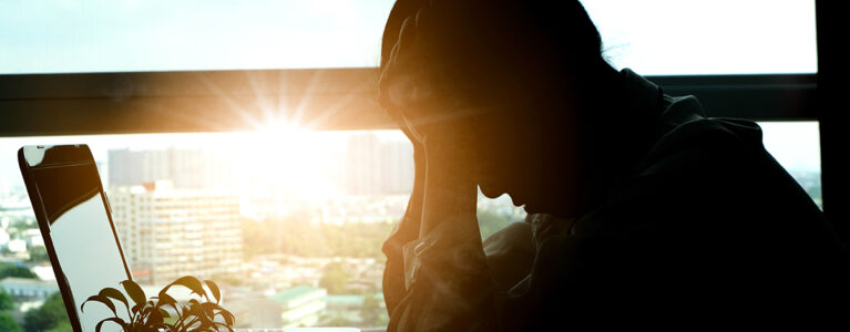 Stressed woman with sun shining in the background.