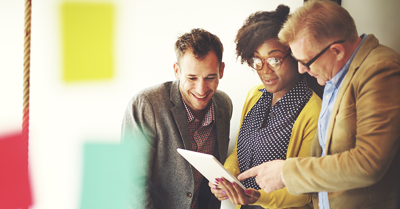 three people looking at a tablet in an office setting