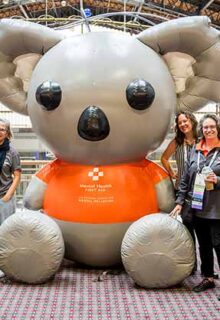 a group of people stand around a large inflatable bear