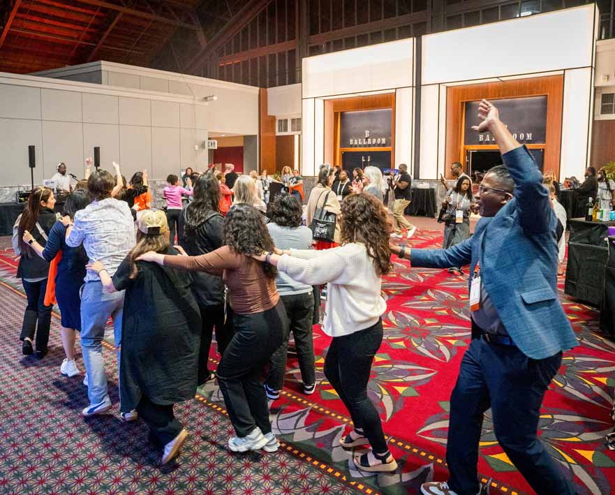 a group of people dance in a line at a conference