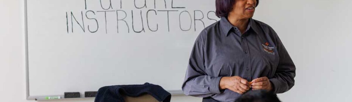 an instructor stands at the front of a classroom