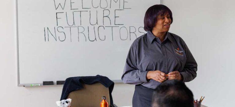 an instructor stands at the front of a classroom