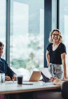 a group of people in a conference room, talking and smiling