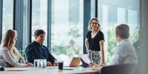 a group of people in a conference room, talking and smiling