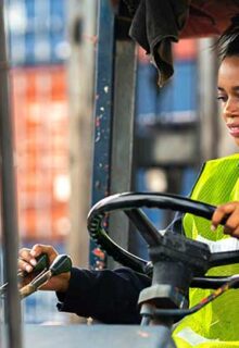 a woman drives a forklift in a warehouse