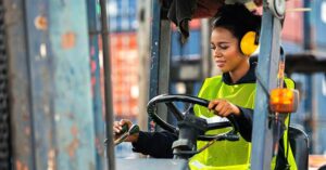 a woman drives a forklift in a warehouse