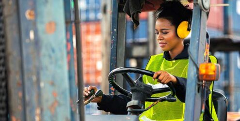 a woman drives a forklift in a warehouse