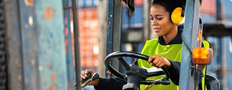 a woman drives a forklift in a warehouse