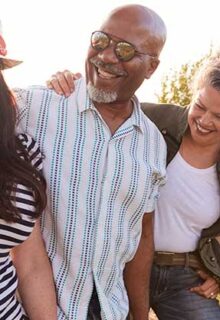 five people walking in the sun smiling and hugging