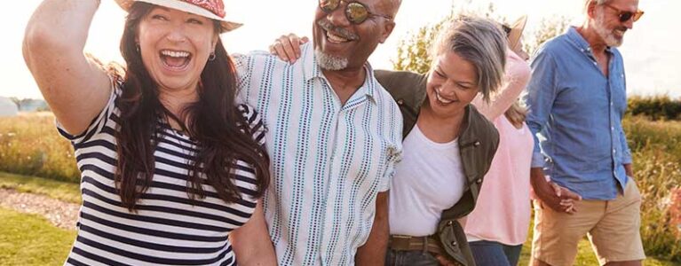 five people walking in the sun smiling and hugging
