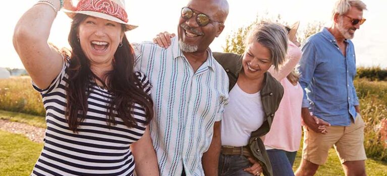 five people walking in the sun smiling and hugging